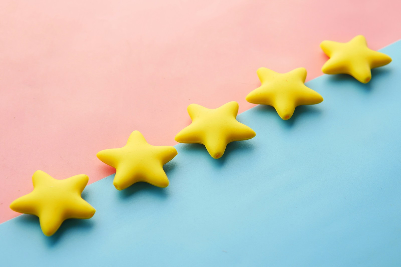 a row of 5 yellow stars sitting on top of a blue and pink surface